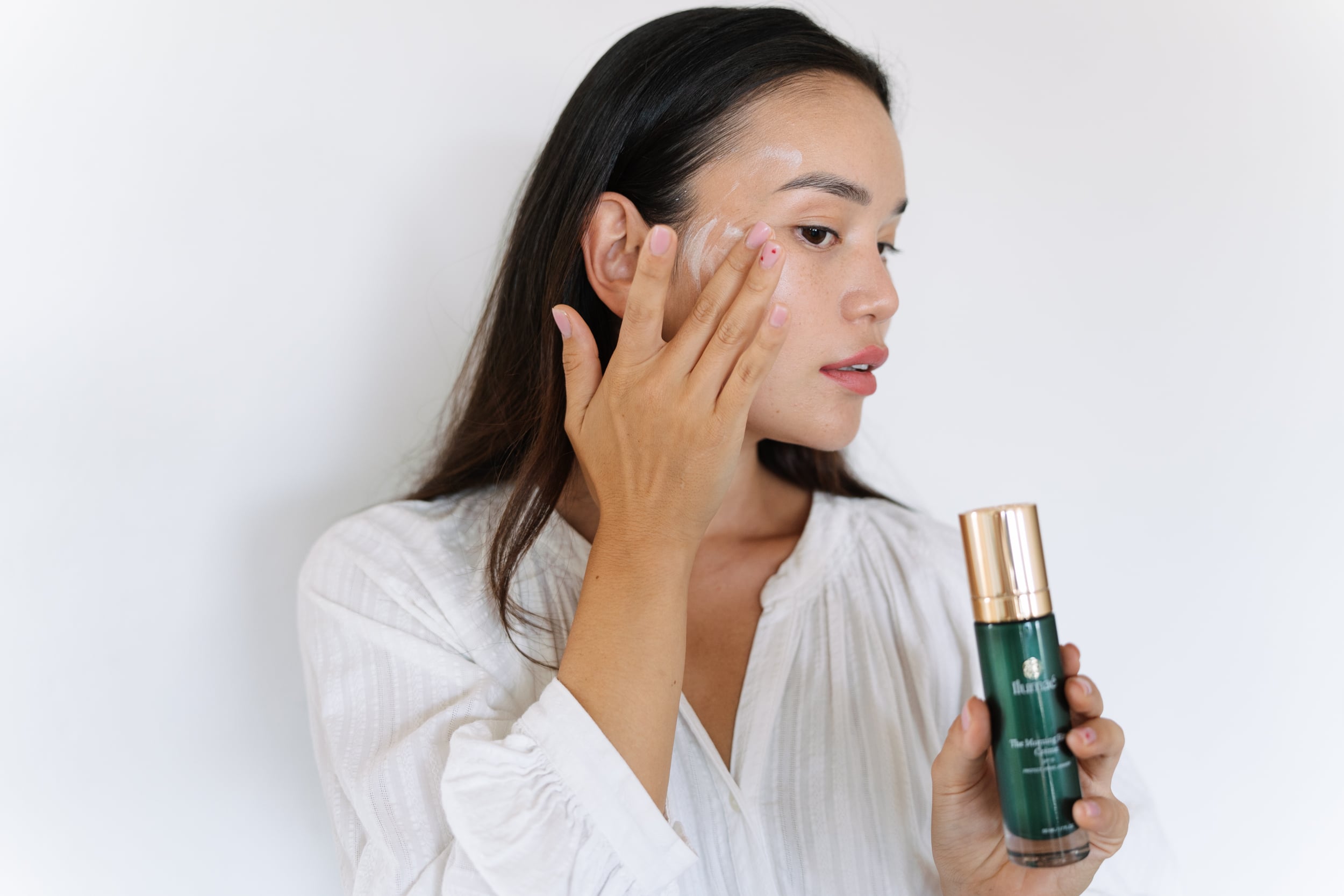 Female applying Ilumaé Skincare product on her skin